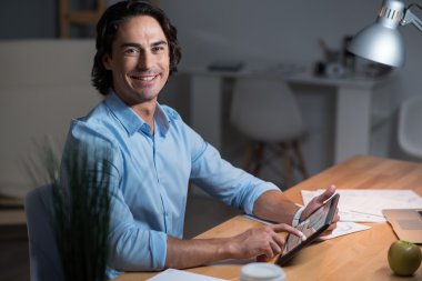 İyi görünümlü gülümseyen genç adam tablet kullanma.