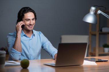 İyi görünümlü gülümseyen genç adam cep telefonu konuşuyor .