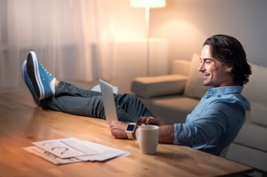 Gülümseyen rahat yang adam dizüstü bilgisayar üzerinde çalışıyor .