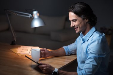 Tablet üzerinde çalışan gülümseyen pozitif genç adam .