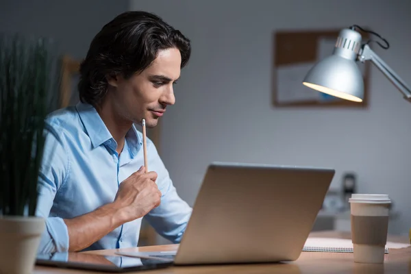 Schöner ernster junger Mann mit Laptop. — Stockfoto