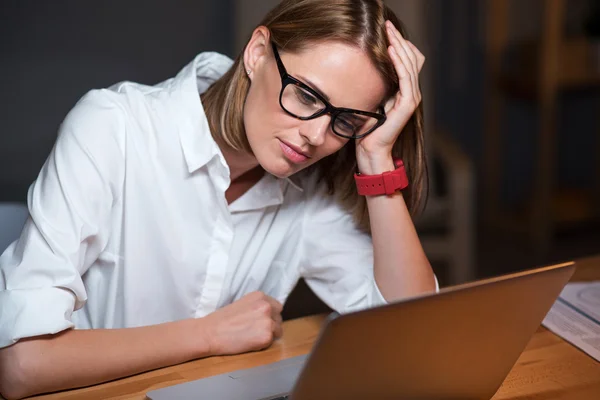 Mulher cansada trabalhando em um laptop — Fotografia de Stock