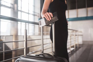 Genç ve güzel bir kadın elinde bir biniş kartı ve bir bavul tutuyor.