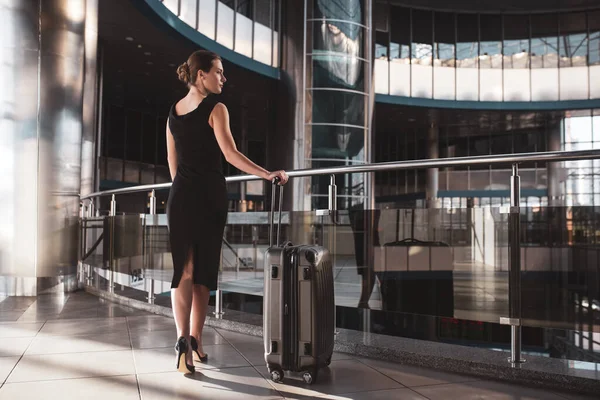 Elegante Frau mit schwarzem Kleid und Koffer — Stockfoto
