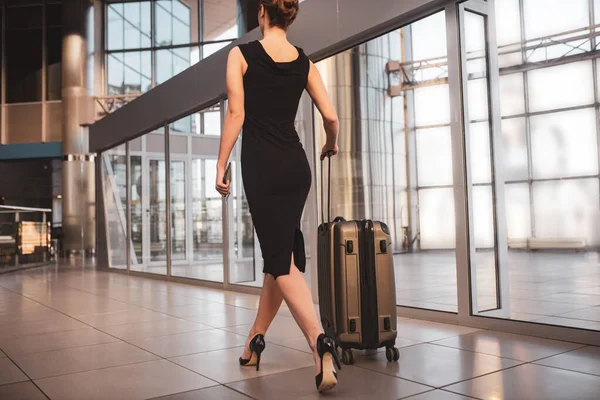Femme portant une robe noire et portant une valise — Photo