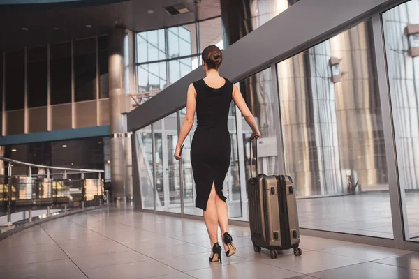 Elegancka kobieta przechodząca przez lotnisko z walizką — Zdjęcie stockowe