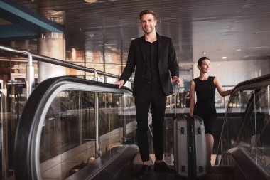 Tren istasyonunda yürüyen merdiven kullanan bir adam ve kadın.