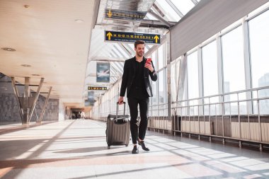 Adam akıllı telefonuyla tren istasyonunda yürüyor.