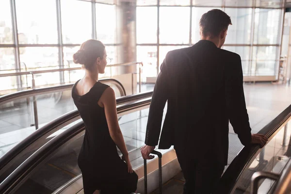 Офіційно одягнена пара використовує ескалатор в аеропорту — стокове фото