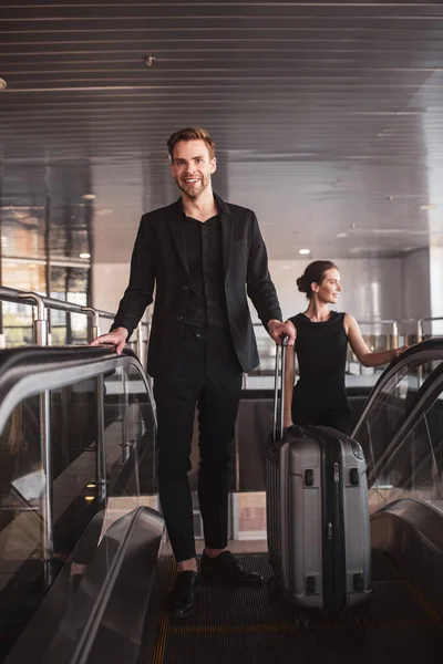 エスカレーターを通ってスーツケースを運ぶ男と女 — ストック写真