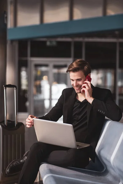 Een man die een telefoontje pleegt terwijl hij wacht op het instappen. — Stockfoto