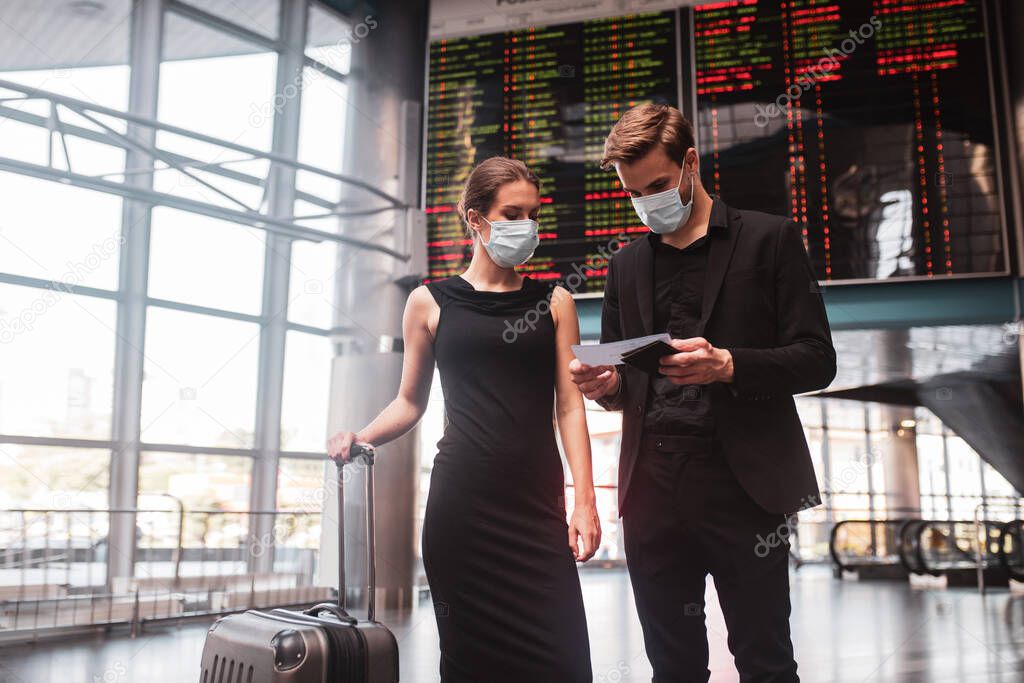 Man and woman wearing face masks preparing for departure