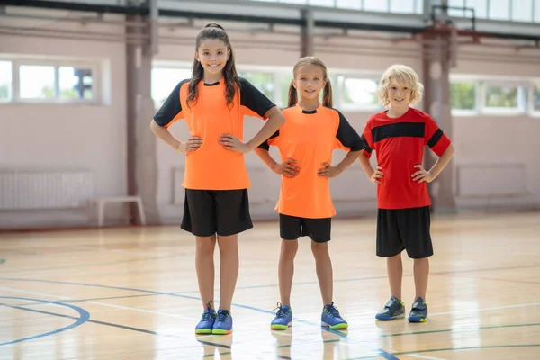 Niños en ropa deportiva brillante de pie con las manos en las caderas — Foto de Stock