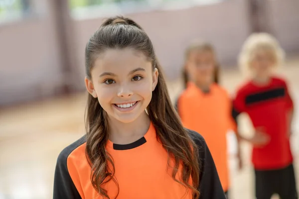 Menina bonito em tshirt laranja sorrindo muito bem — Fotografia de Stock