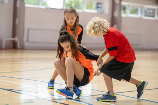 Enfants en vêtements de sport lumineux aider leur ami dans la salle de gym — Photo