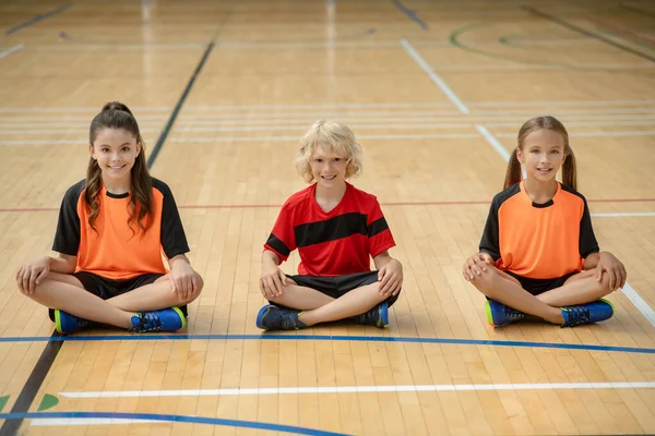 Niños en ropa deportiva brillante sentados en pose de loto — Foto de Stock