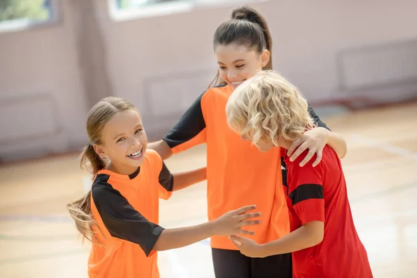 Niños en ropa deportiva brillante abrazándose y sintiéndose alegres — Foto de Stock