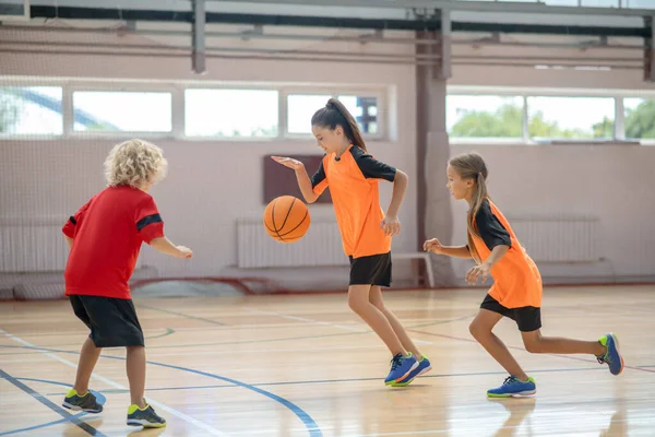 Kinder in heller Sportbekleidung spielen gemeinsam Basketball und fühlen sich eingebunden — Stockfoto