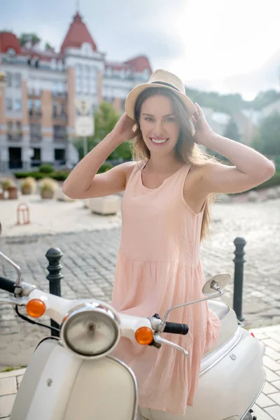 Mujer alegre montando un pequeño scooter blanco — Foto de Stock