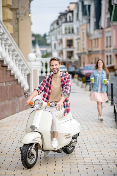 Fröhlicher junger Mann auf seinem weißen Roller — Stockfoto