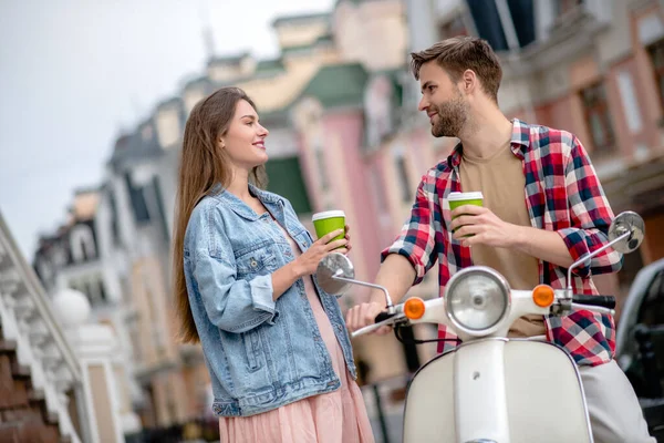 Man dricker kaffe med sin flickvän när man åker skoter — Stockfoto