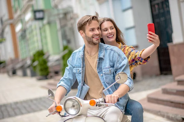 Mujer tomando una selfie mientras monta un scooter — Foto de Stock