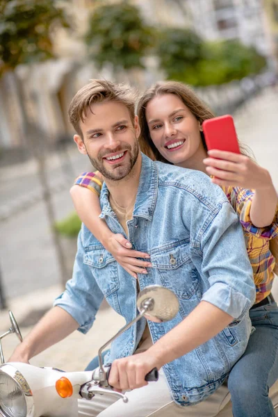 Mujer tomando foto con su novio ridig un scooter — Foto de Stock