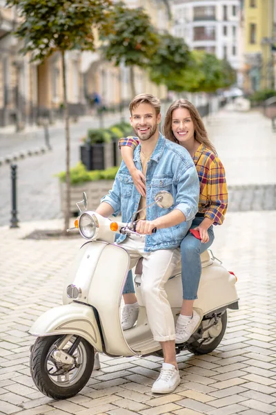 Mujer abrazando a un hombre mientras monta un scooter — Foto de Stock