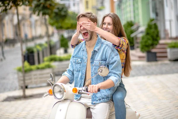 Žena zavírající její přítel oči při jízdě na skútru — Stock fotografie