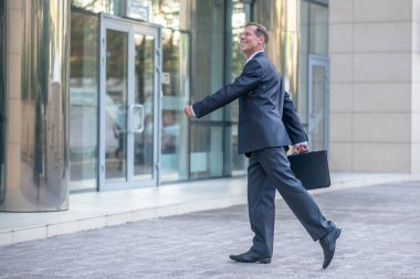 Gülümseyen olgun iş adamı iş merkezine giriyor.