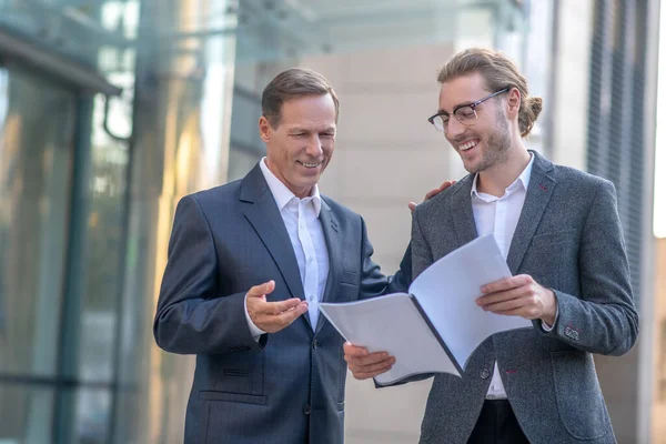 Twee betrokken mannelijke collega 's die documenten bestuderen en buiten discussiëren — Stockfoto