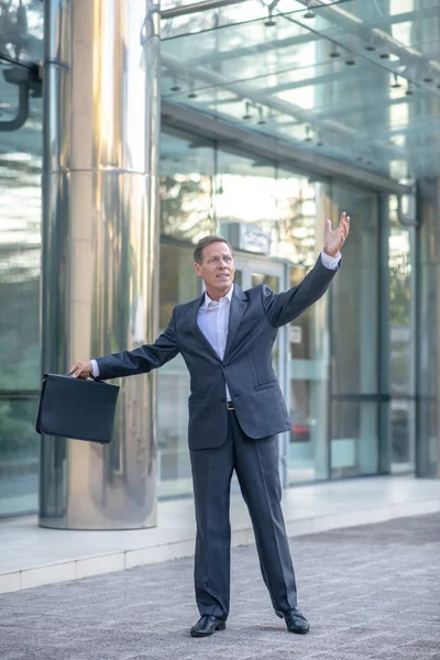 Volwassen zakenman staat buiten, zwaaiend, iemand roepend — Stockfoto