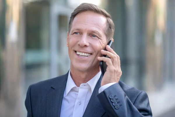 Glimlachende volwassen zakenman hebben gesprek via de telefoon buiten — Stockfoto