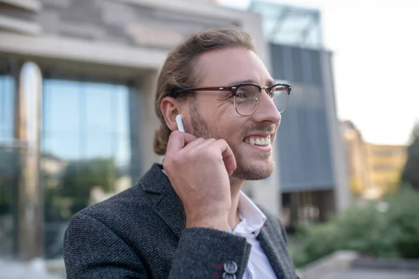 Travailleur de bureau souriant portant des écouteurs sans fil à l'extérieur — Photo