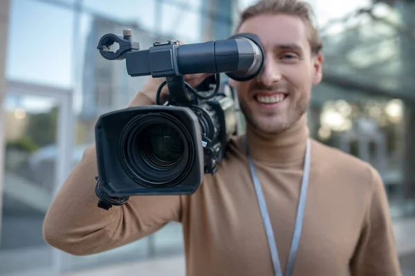 Camarógrafo sonriente sosteniendo la cámara en su hombro, mirando a los ojos —  Fotos de Stock