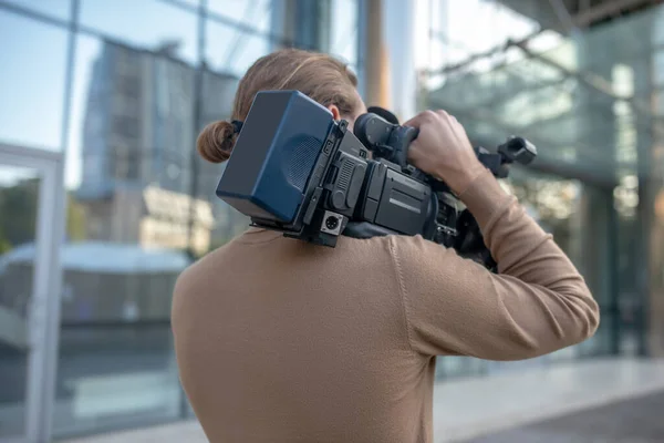 Vista trasera del camarógrafo cargando la cámara en su hombro —  Fotos de Stock