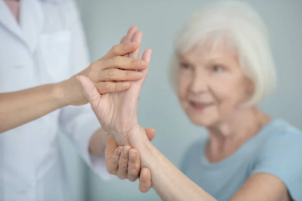 Doktor yaşlı bir kadının bileğini muayene ediyor. — Stok fotoğraf