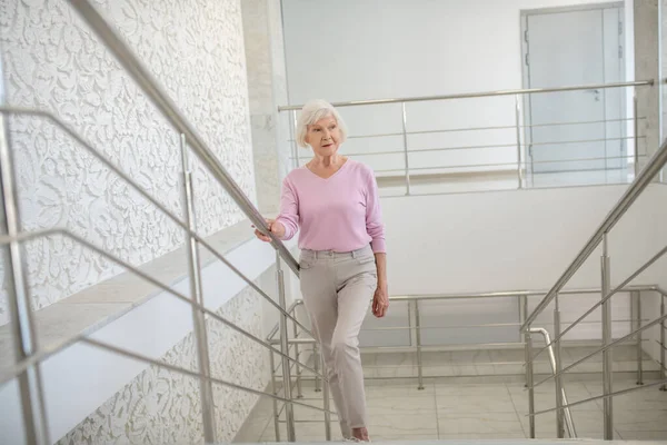 Mujer mayor con una camisa rosa subiendo lentamente — Foto de Stock