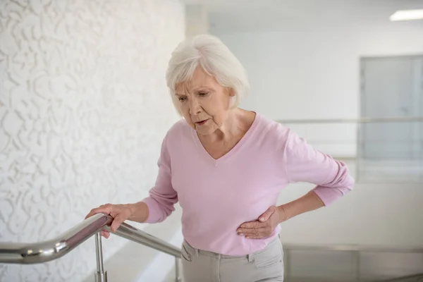 Ältere Frau im rosa Hemd leidet unter Schmerzen — Stockfoto