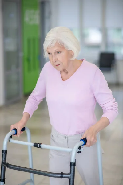 Mujer mayor caminando con un caminante rodante — Foto de Stock