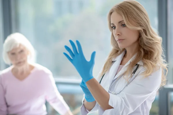 Joven enfermera guapa de pelo largo con guantes protectores — Foto de Stock