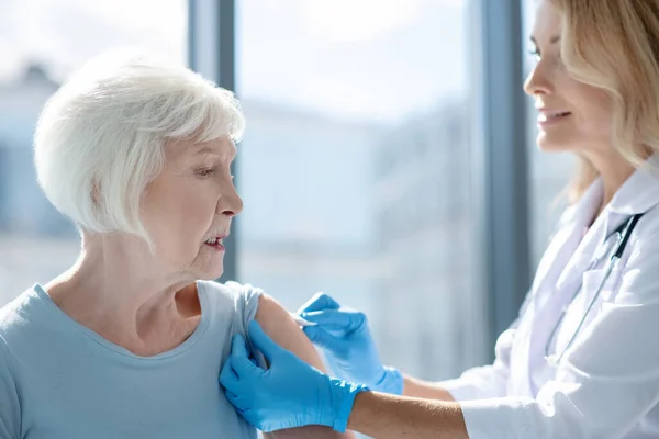 Hübsche junge Krankenschwester macht einer älteren Frau eine Spritze — Stockfoto