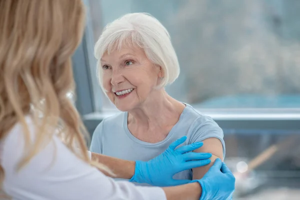 Långhårig kvinnlig sjuksköterska som vaccinerar en äldre kvinna — Stockfoto