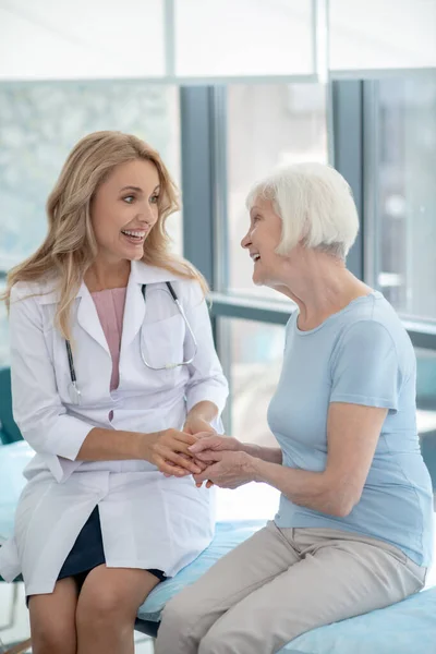 Μακρυμάλλης χαριτωμένη νοσοκόμα μιλάει σε έναν ηλικιωμένο ασθενή — Φωτογραφία Αρχείου
