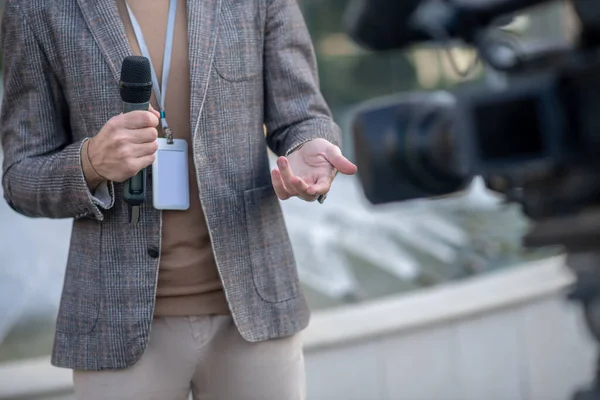 Großaufnahme männlicher Reporterhände mit Mikrofon vor der Kamera — Stockfoto