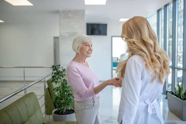 Ősz hajú nő kezet rázott az orvossal a klinikán. — Stock Fotó