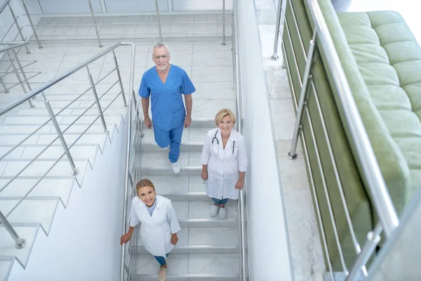 Équipe de travailleurs médicaux souriants descendant les escaliers — Photo