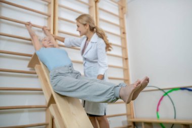 Rehabilitasyon merkezinde eğitmenle egzersiz yapan yaşlı bir hasta.