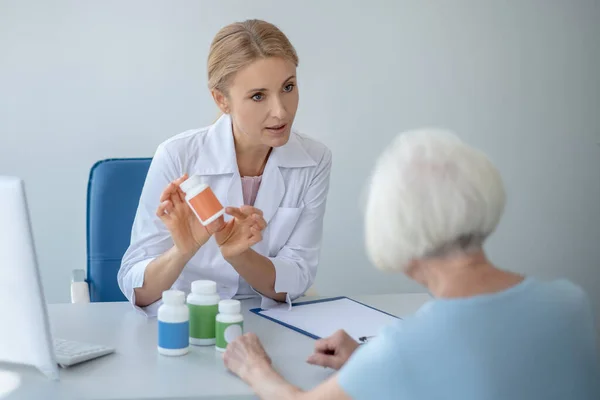 Kvinna läkare ordinerar läkemedel till äldre patienter — Stockfoto