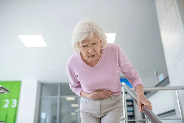 Grauhaarige Frau in lässiger Kleidung mit Bauchschmerzen — Stockfoto